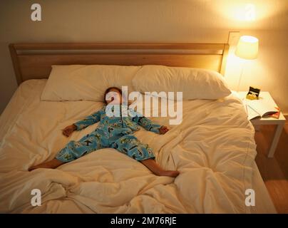 He always sleeps so peacefully. a young boy sleeping in bed. Stock Photo