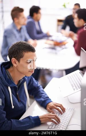 Focused on meeting the next deadline. a young man working on his laptop in an office. Stock Photo