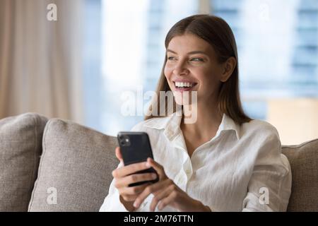 Attractive young woman resting on sofa with modern smartphone Stock Photo