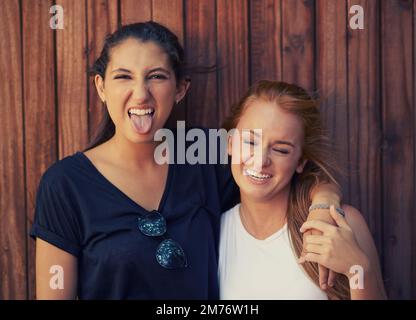 True friends can act the fool together. Two beautiful young girls having fun while spending time together outside. Stock Photo