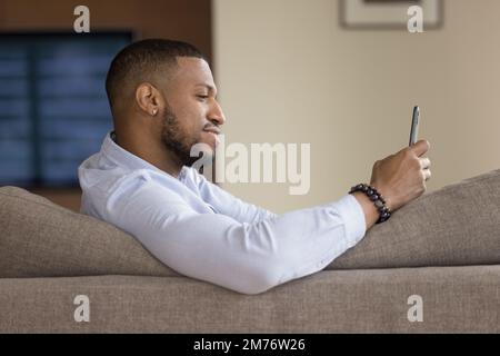 African man resting sit on sofa with smart phone Stock Photo