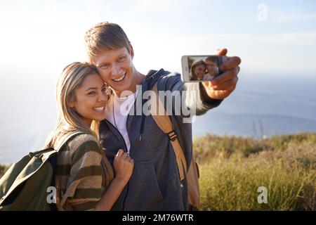 We were here. a happy young couple taking a photo of themselves with their cellphone. Stock Photo