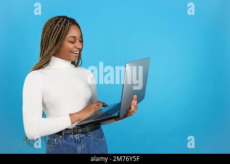 Happy african woman standing while using a laptop Stock Photo