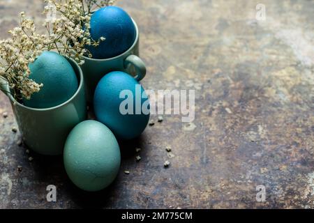 Happy Easter rustic concept. DIY dyed various shades of blue Easter eggs on retro rusty metal background. Stock Photo