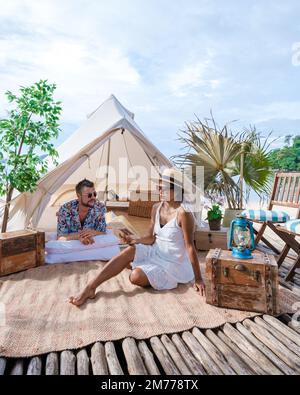 couple camping on the beach, men and women in front of a tent on the beach in Thailand Stock Photo