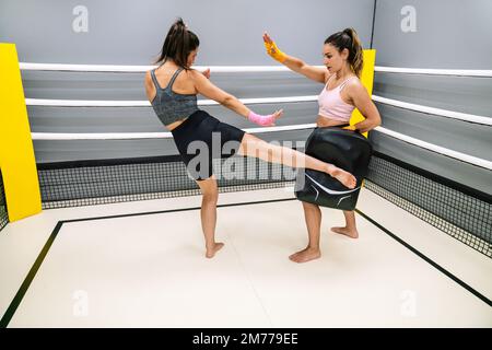 Athlete practicing low kick with her partner in the ring at a kickboxing gym Stock Photo