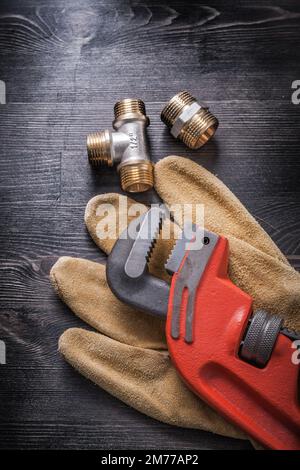 Monkey wrench brass plumbing fittings leather protective gloves construction concept. Stock Photo