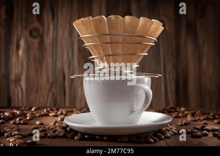 Alternative Coffee Brewing. Corded Paper Filter Holder On White Ceramic Coffee Cup. Coffee Beans On Vintage Wooden Background. Stock Photo