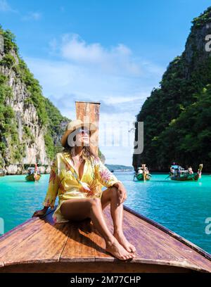 Asian women in front of a longtail boat at Kho Phi Phi Thailand, women in front of a boat at Pileh Lagoon Stock Photo