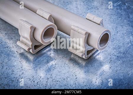 Plastic water-pipes pipe clamps on metallic background construction concept. Stock Photo