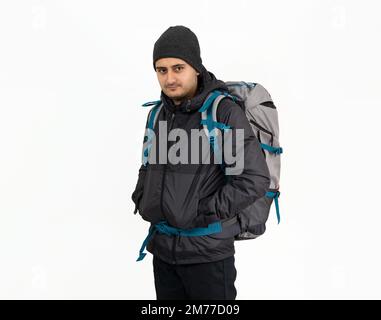 Studio photo of Brown skinned young backpacker, camper or hiker standing on isolated background. Concept of trekking or nature walking. Stock Photo