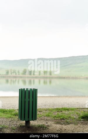 Green trash can on the shore of the lake Lisi Park in Tbilisi, Georgia Stock Photo