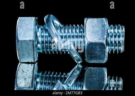 Stainless nut screwbolt spring washer on black surface. Stock Photo