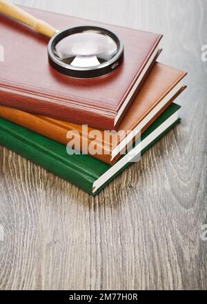 three notebooks and magnifier Stock Photo