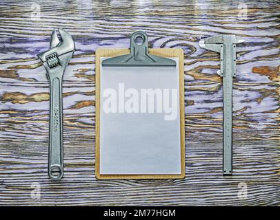 Vernier caliper adjustable spanner clipboard on wooden board. Stock Photo