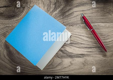 Vintage blue notepad red ballpoint pen on wooden board. Stock Photo