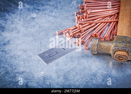 Vintage claw hammer copper construction nails metal ruler on metallic background. Stock Photo