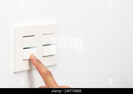 Close up the male hand or fingers turn on or off the white light switch at home with copy space. Stock Photo