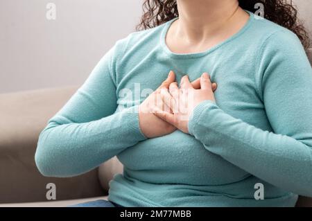 Shot of a mature woman suffering from chest pain while sitting on the sofa at home Stock Photo