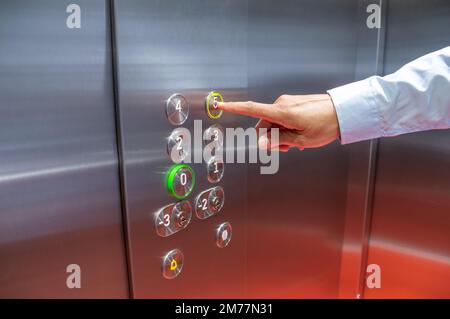 Closeup shot of an unrecognisable man pushing a button in an elevator Stock Photo