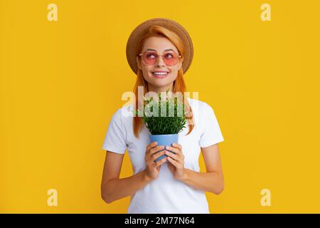 Summer gardener woman isolated on yellow background. Redhead funny girl planting flowers in pot. Stock Photo