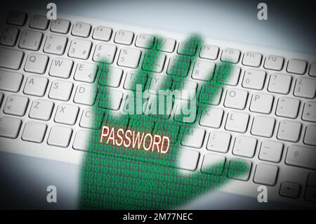 A threatening hand shadow with password on a computer keyboard Stock Photo