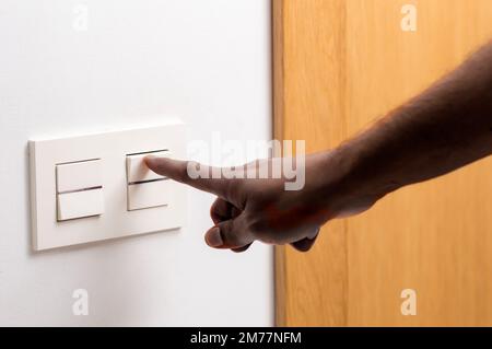 Close up of man hand turning on the light with a wall switch at home Stock Photo