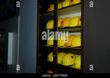Yellow helmets of mine workers on the shelf with white wall at the background Stock Photo