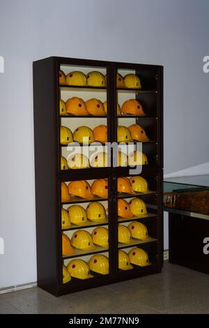 Yellow helmets of mine workers on the shelf with white wall at the background Stock Photo