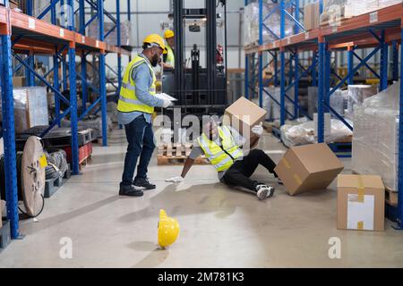 African american working in warehouse got accident from carry box, forklift truck working near by Stock Photo