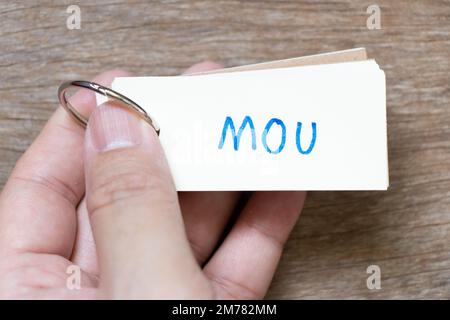 Hand hold flash card with handwriting in word MOU (Abbreviation of memorandum of understanding) on wood background Stock Photo