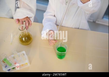 Selective focus: kids performing chemical experiments, using graduated pipette, beaker, test tubes at chemistry class Stock Photo