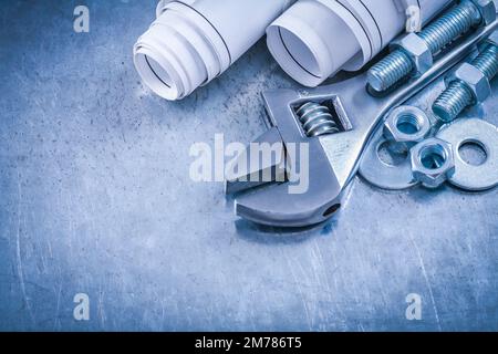 Adjustable key bolt washers screw-nuts screwbolts and blueprint rolls on scratched metallic background maintenance concept. Stock Photo