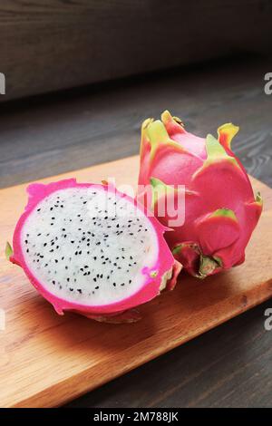 Fresh Ripe Dragon Fruit Cut in Half with a Whole Fruit on Wooden Chopping Board Stock Photo