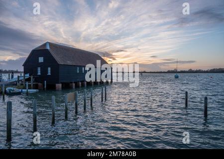 Raptackle wooden hut in Bosham West Sussex England over the sea with the sun going down in the background Stock Photo