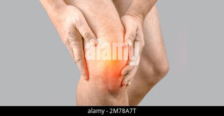 Man with knee pain on gray background. Man leg knee with red dot. Knee injury, sprain, arthritis or meniscus. Man having problems in knee joint. Close Stock Photo