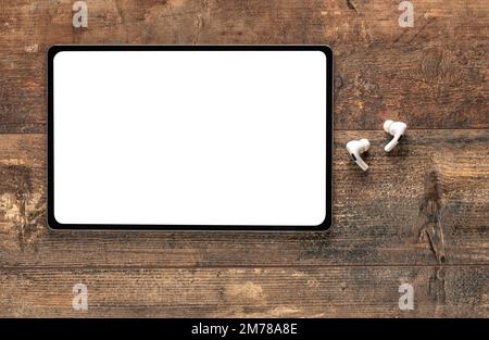 Mockup tablet. top view of blank screen tablet, wireless earphone on old rustic wooden table. Top view blank screen tablet on wooden table with copy s Stock Photo