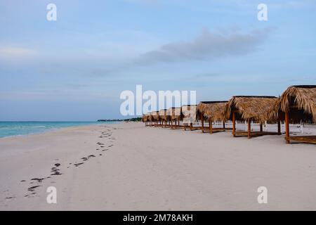 Beach chairs and umbrellas at pre-sunset time on an empty beach. Stock Photo