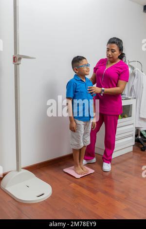 Pediatric doctor weighing a child in her office with a floor scale. Stock Photo