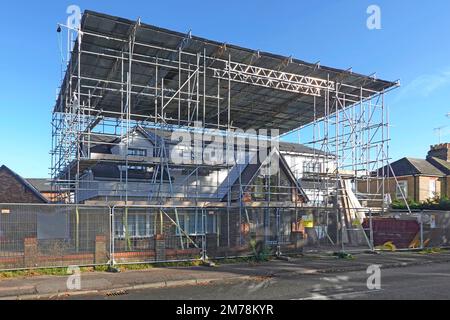 Building construction bungalow conversion to house vertical plastic sheeting removed corrugated roof on scaffolding ladder beam framework remains UK Stock Photo