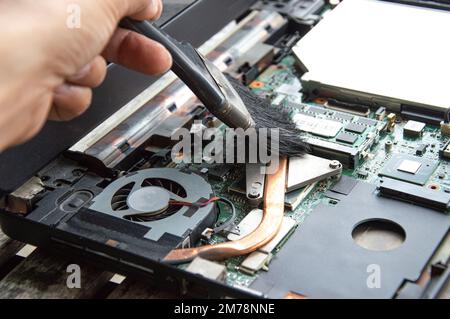 technician using brush Clean the dusty notebook. Stock Photo