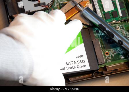 Technician installing ssd drive in old computer, upgrading computer Stock Photo