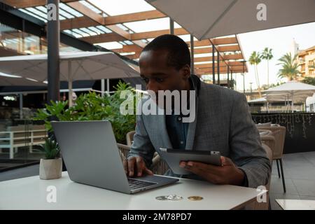 Bitcoin trader monitors the market through laptop and tablet with full concentration Stock Photo