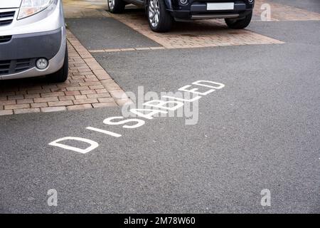 Disabled car parking bays with the word disabled painted in white on tarmac asphalt surface Stock Photo