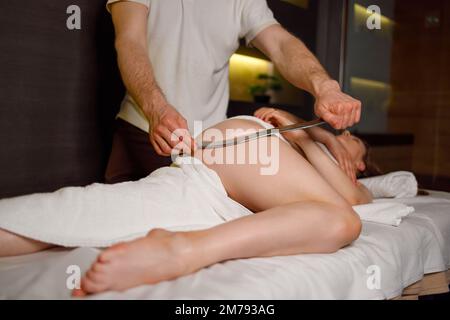 Therapist using IASTM instrument for soft tissue treatment on the female legs Stock Photo