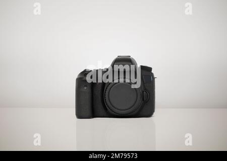 Camera isolated on a white background. The camera is placed on a glossy surface that reflects the shape of the camera Stock Photo