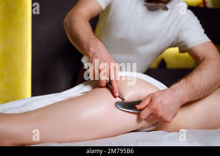 Massage therapist performs a buttocks massage using tools for mobilization of soft tissues Stock Photo