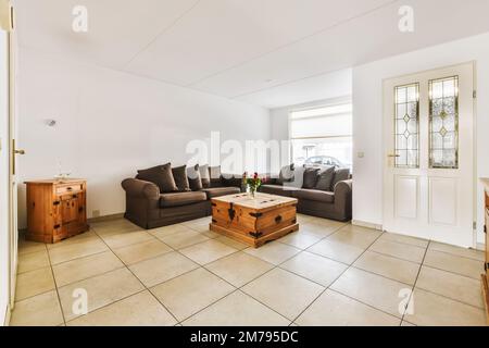 a living room with two couches and a coffee table in front of the sofa is on the tiled floor Stock Photo