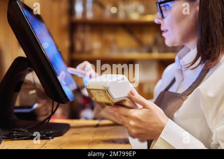 Female restaurant worker using computer terminal while serving customers Stock Photo