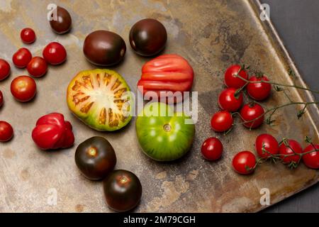 Green, brown and red tomatoes. Branch of cherry tomato. Flat lay. Rusty metal background. Stock Photo